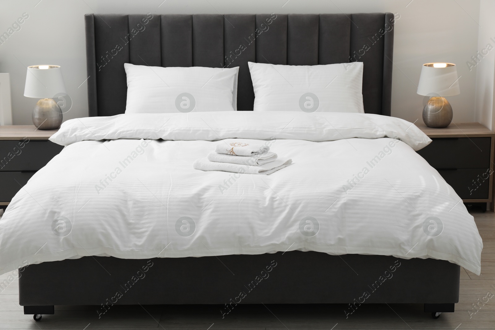 Photo of Comfortable bed with clean linens, pillows and towels indoors