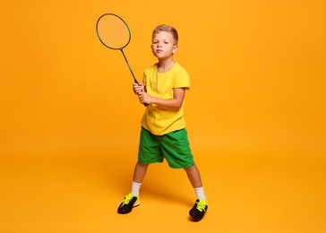 Photo of Little boy with badminton racket on orange background