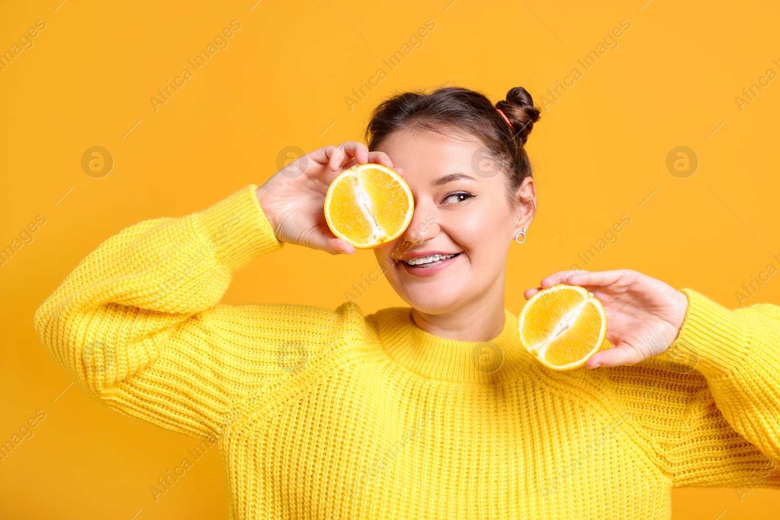 Photo of Happy young woman with halves of citrus fruit on orange background