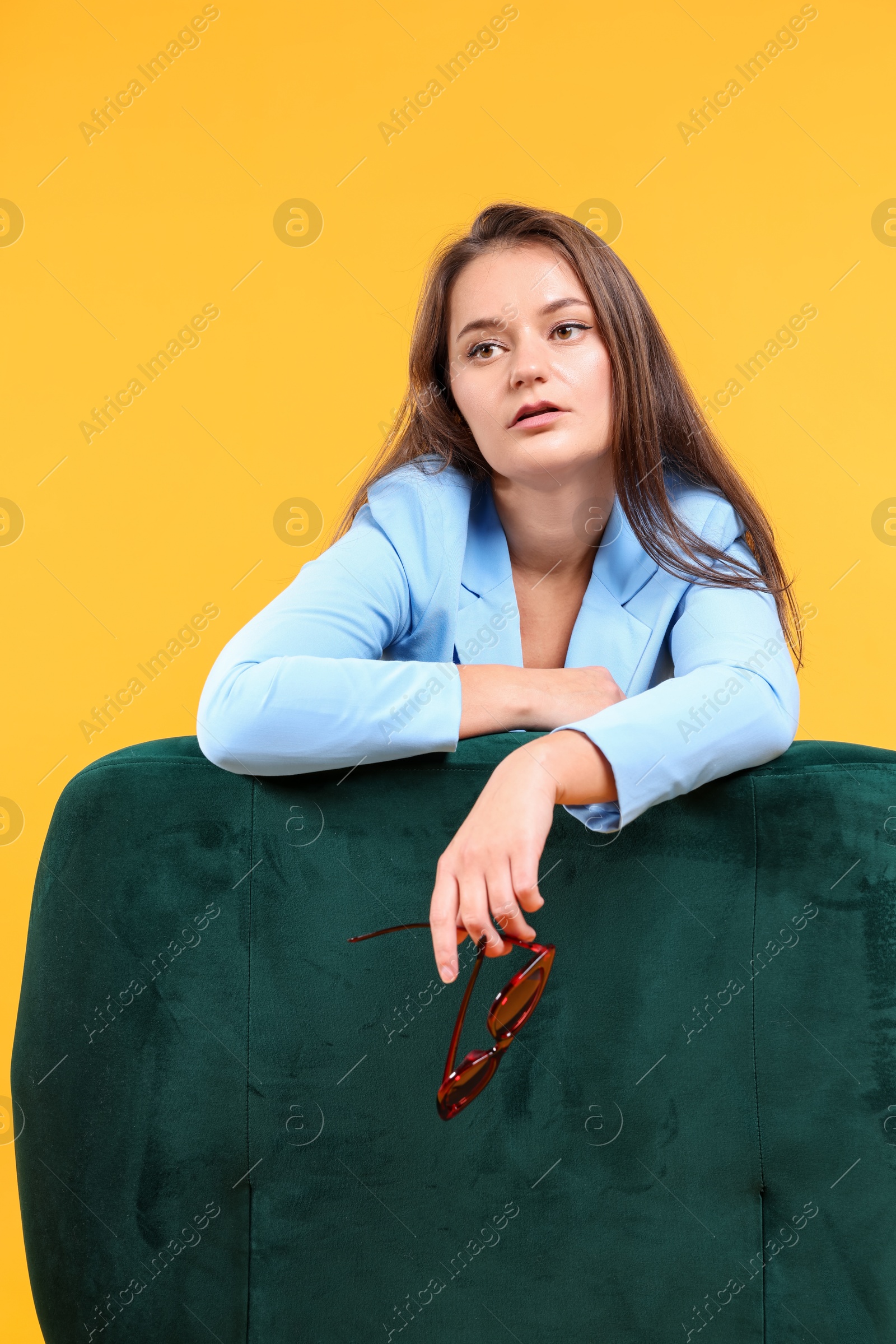 Photo of Fashion portrait of woman in light blue jacket on yellow background