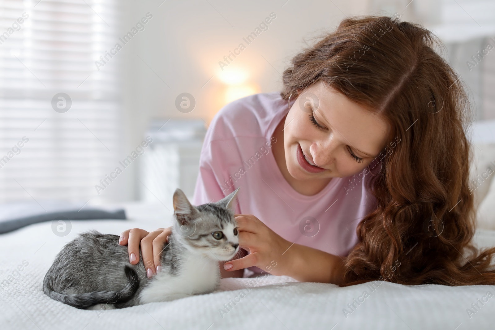 Photo of Beautiful teenage girl with cute cat on bed at home