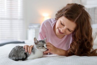 Photo of Beautiful teenage girl with cute cat on bed at home