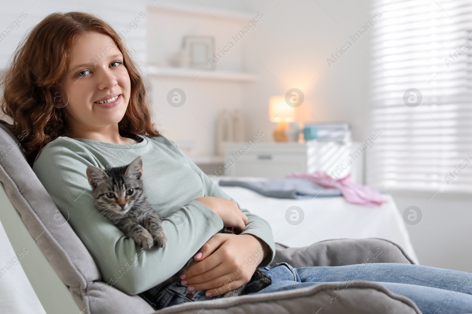 Photo of Beautiful teenage girl with cute cat on sofa at home