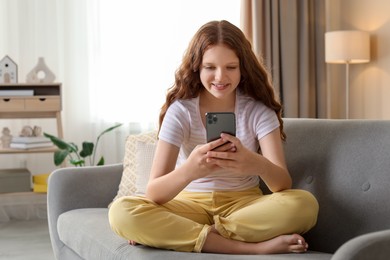 Photo of Beautiful teenage girl using smartphone on sofa at home