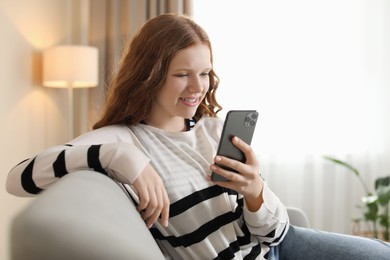 Photo of Beautiful teenage girl using smartphone on sofa at home