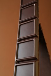 Pieces of tasty chocolate bar on brown background, closeup