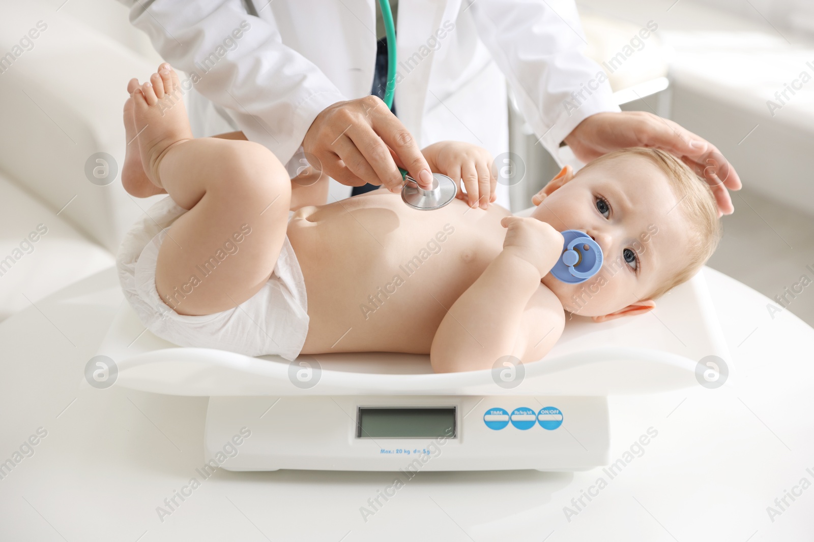 Photo of Pediatrician examining little child with stethoscope in clinic, closeup. Checking baby's health