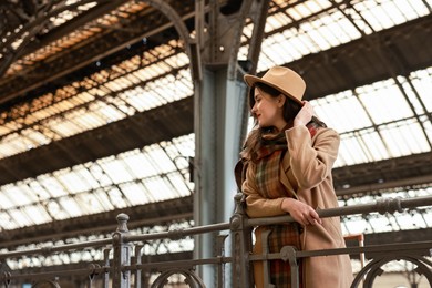 Photo of Beautiful woman in hat at railway station, space for text