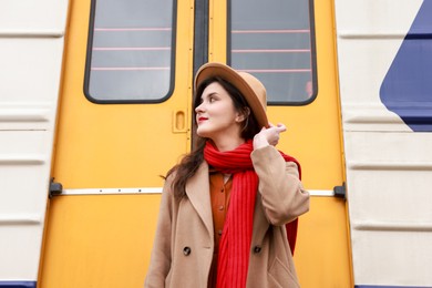 Photo of Beautiful woman with red scarf near train outdoors, low angle view