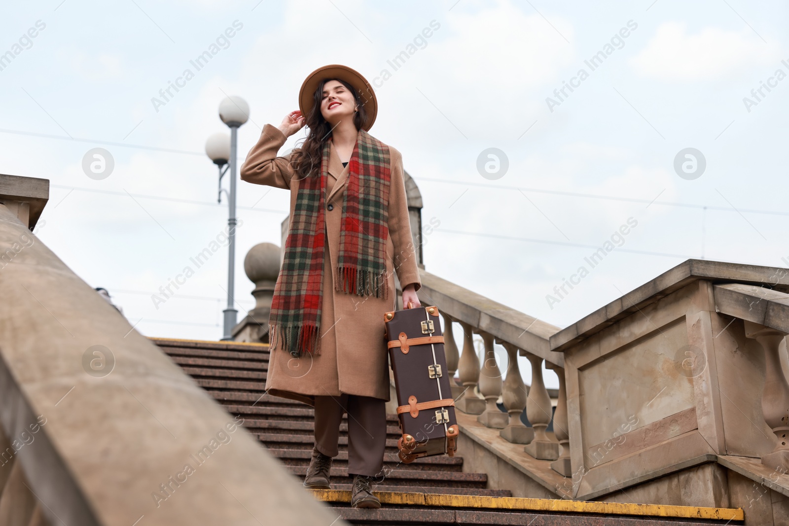 Photo of Beautiful woman with suitcase on stairs outdoors, low angle view