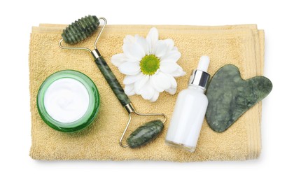 Photo of Face roller, cosmetic products, towel, gua sha and flower isolated on white, top view