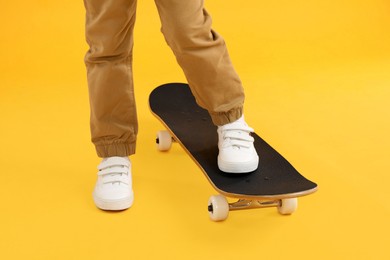 Photo of Little boy with skateboard on yellow background, closeup