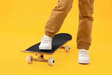 Photo of Little boy with skateboard on yellow background, closeup