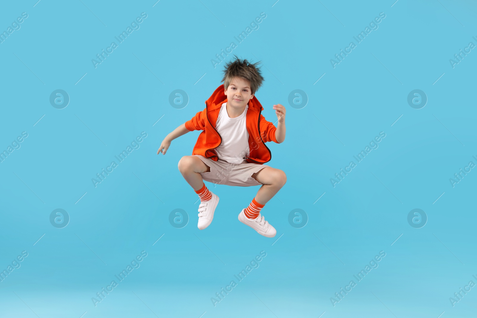 Photo of Happy little boy jumping on light blue background