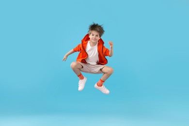 Photo of Happy little boy jumping on light blue background