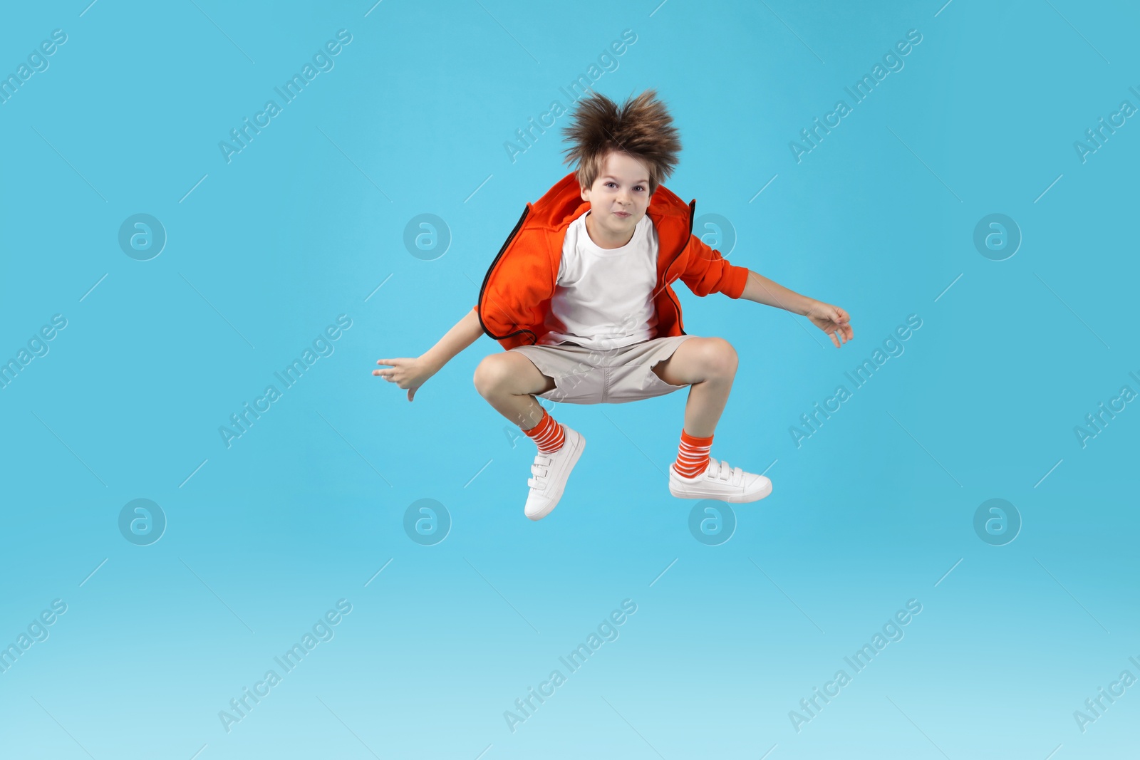 Photo of Happy little boy jumping on light blue background