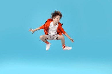 Photo of Happy little boy jumping on light blue background