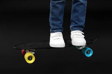 Photo of Little boy with skateboard on black background, closeup