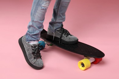 Photo of Little girl with penny board on pink background, closeup