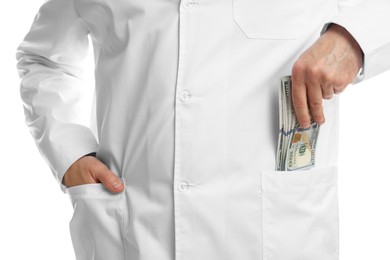 Corruption concept. Doctor putting dollar banknotes into his pocket on white background, closeup