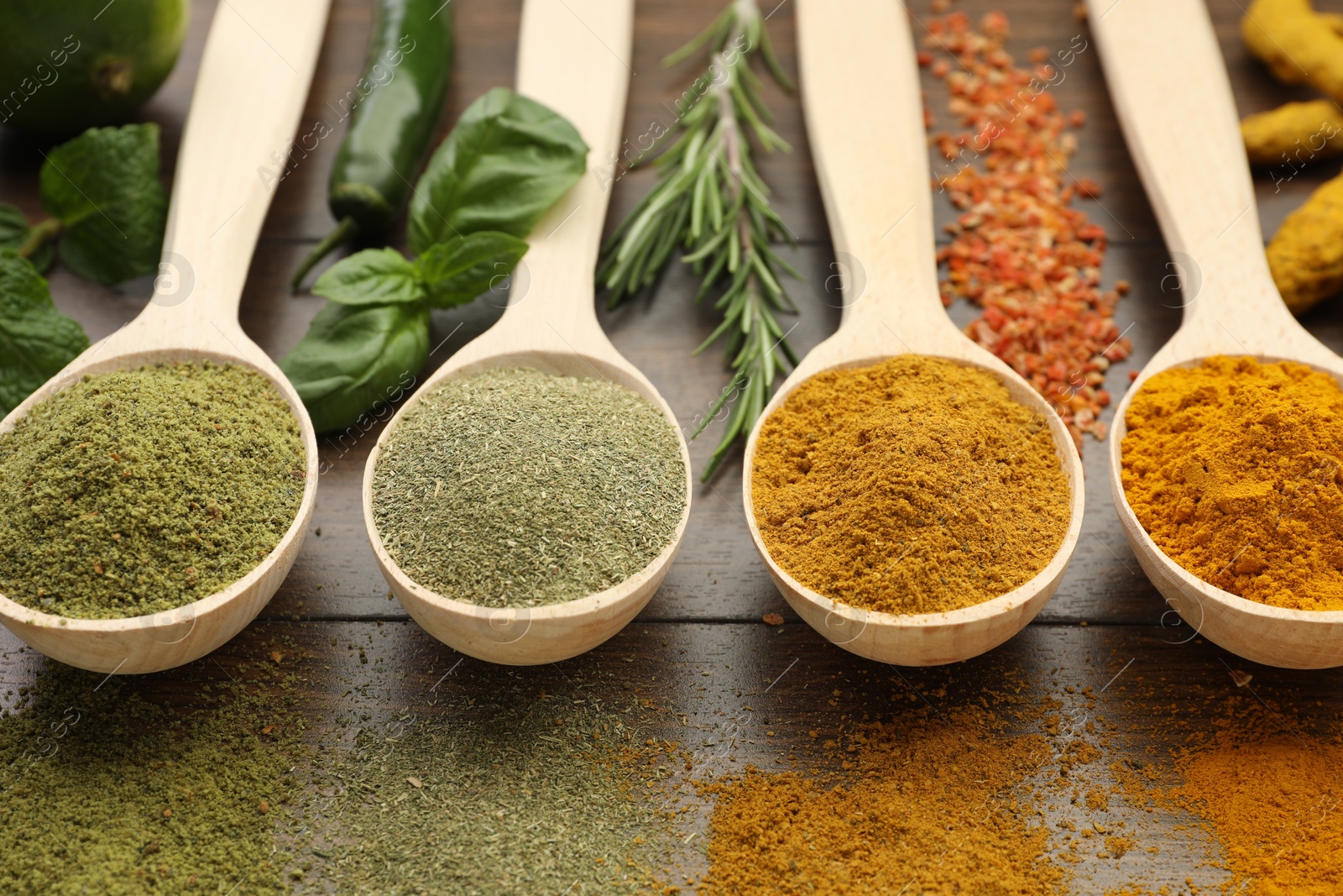 Photo of Different aromatic spices and herbs on wooden table, closeup