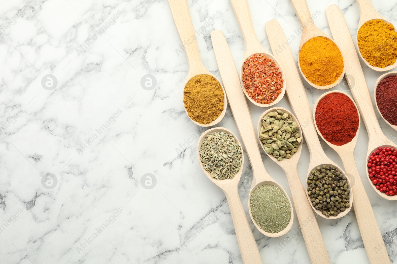 Photo of Different aromatic spices in spoons on white marble table, flat lay. Space for text