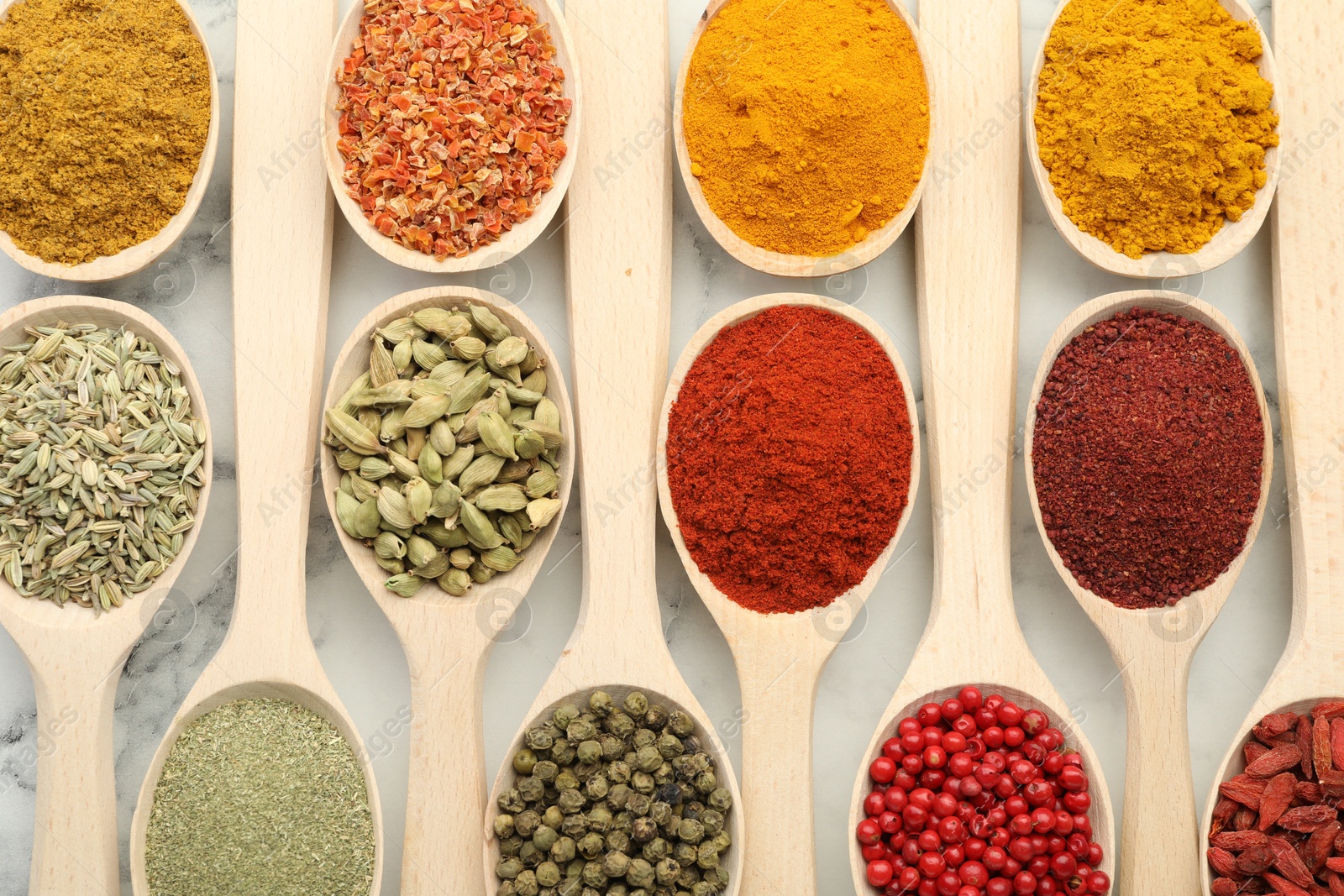 Photo of Different aromatic spices in spoons on white marble table, flat lay