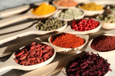 Photo of Different aromatic spices in spoons on table, closeup