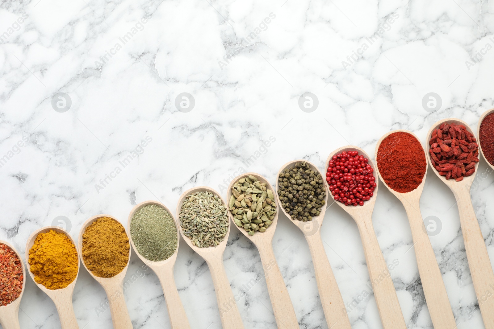 Photo of Different aromatic spices in spoons on white marble table, flat lay. Space for text