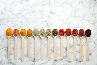 Photo of Different aromatic spices in spoons on white marble table, flat lay. Space for text