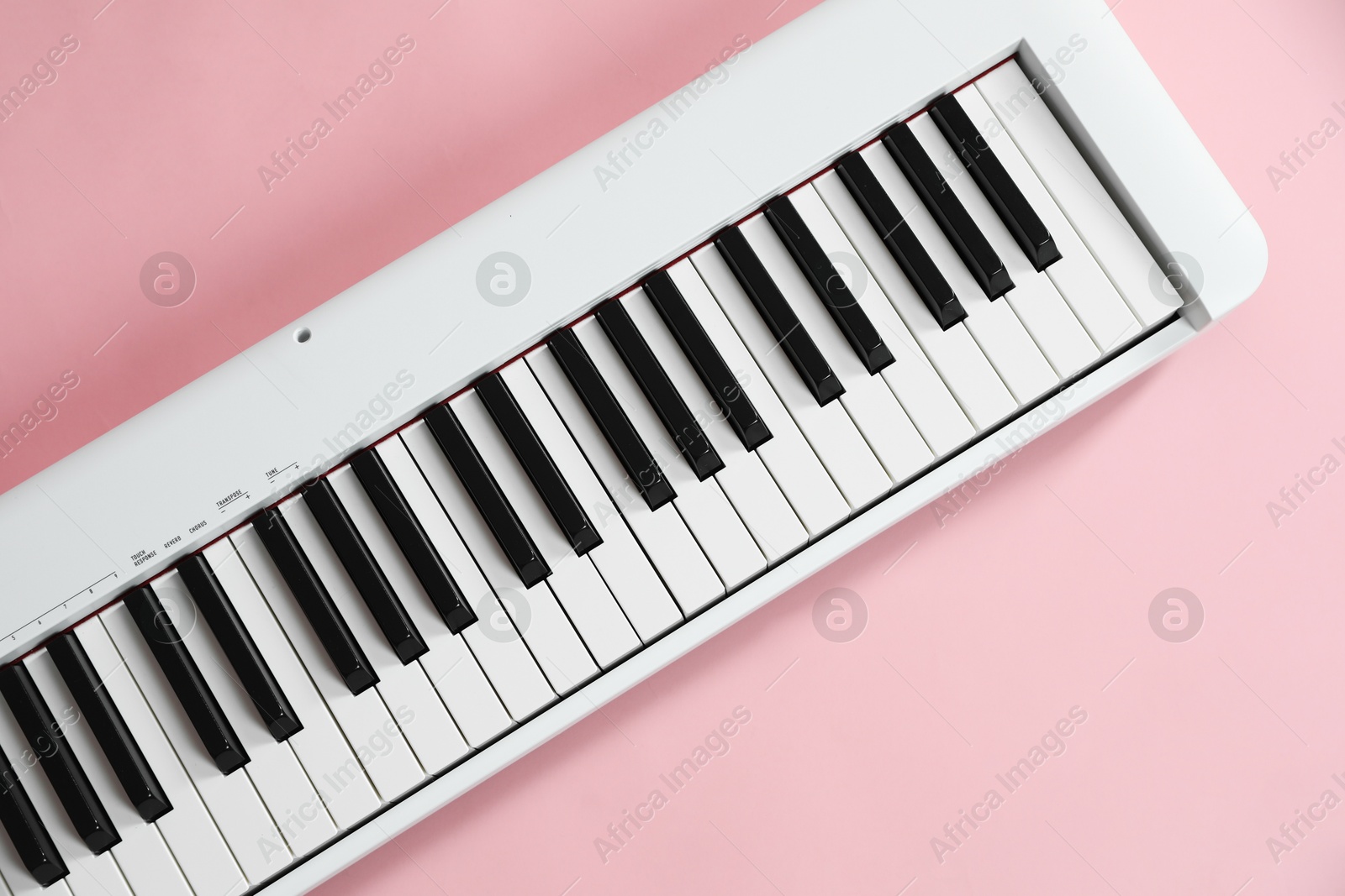 Photo of Synthesizer on pink background, top view. Electronic musical instrument