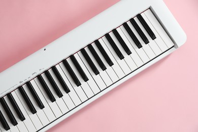 Photo of Synthesizer on pink background, top view. Electronic musical instrument