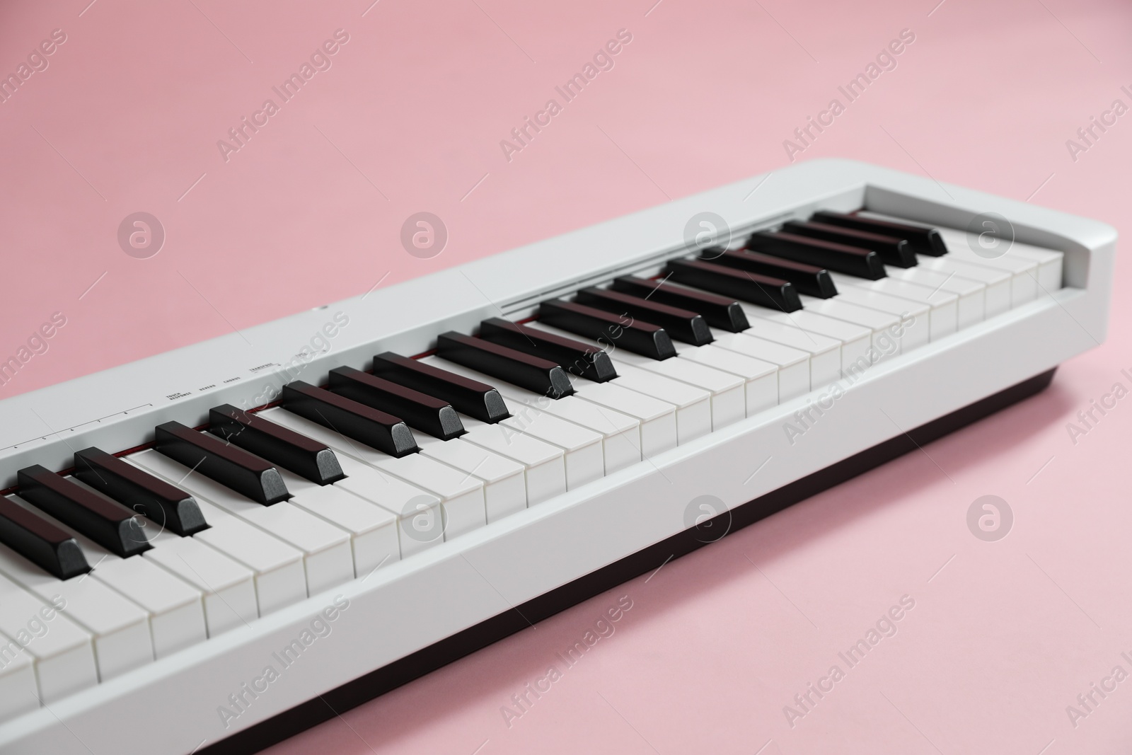 Photo of Synthesizer on pink background, closeup. Electronic musical instrument