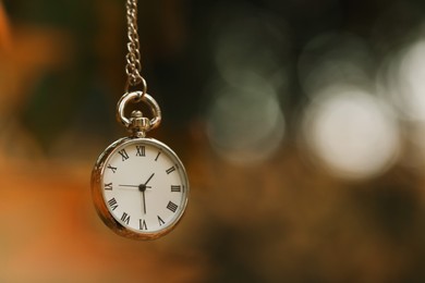 Photo of Autumn time. Chain watch on blurred background, closeup with space for text