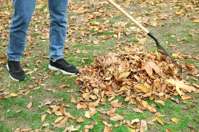 Photo of Man gathering fallen leaves with fan rake outdoors, closeup