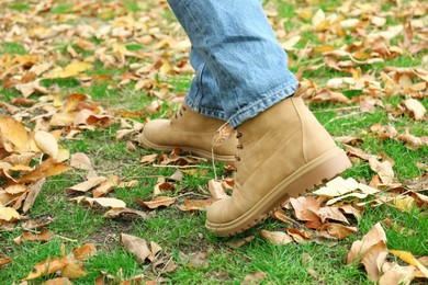 Photo of Man walking on green grass with fallen leaves, closeup