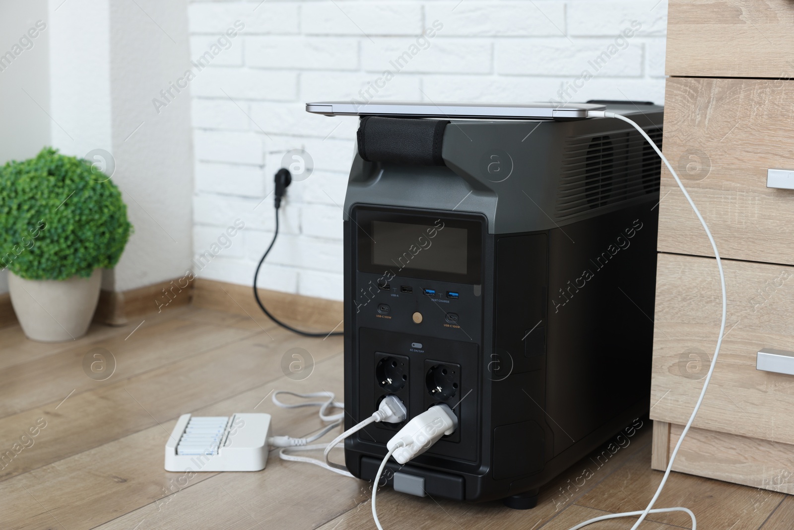 Photo of Modern portable power station, charging attached devices indoors