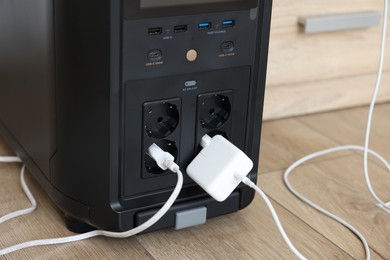 Photo of Modern portable power station on floor indoors, closeup