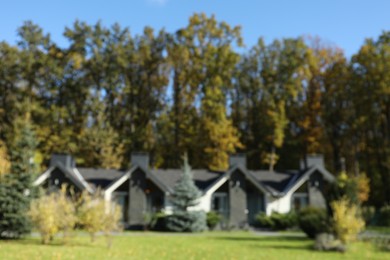 Photo of Blurred view of hotel buildings and different plants in autumnal park