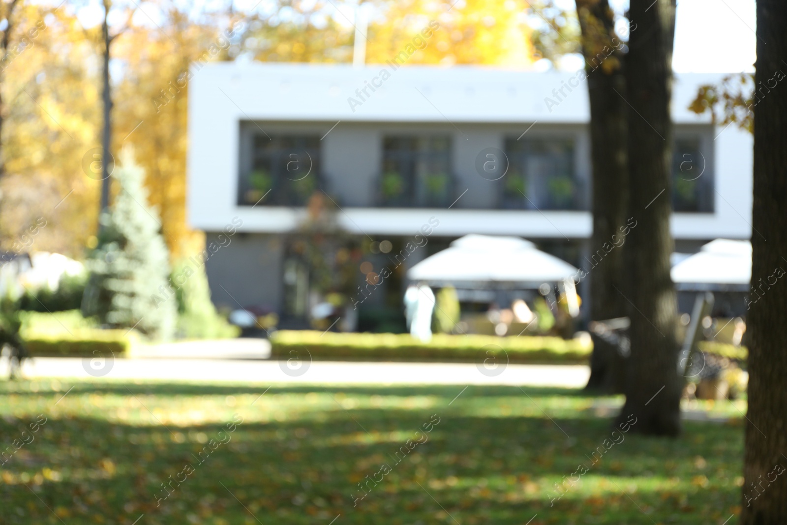 Photo of Blurred view of modern hotel with outdoor cafe. Autumn vacation