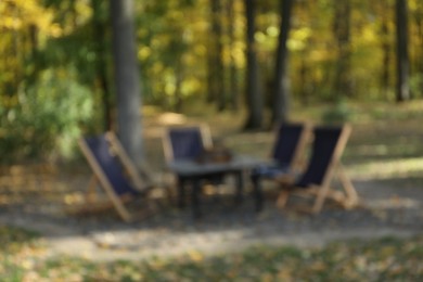 Photo of Blurred view of beautiful autumnal park with picnic table and chairs