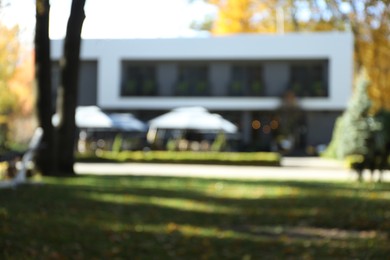 Blurred view of modern hotel with outdoor cafe. Autumn vacation