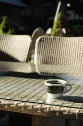 Photo of Table with cup of coffee and chairs in outdoor cafe, closeup