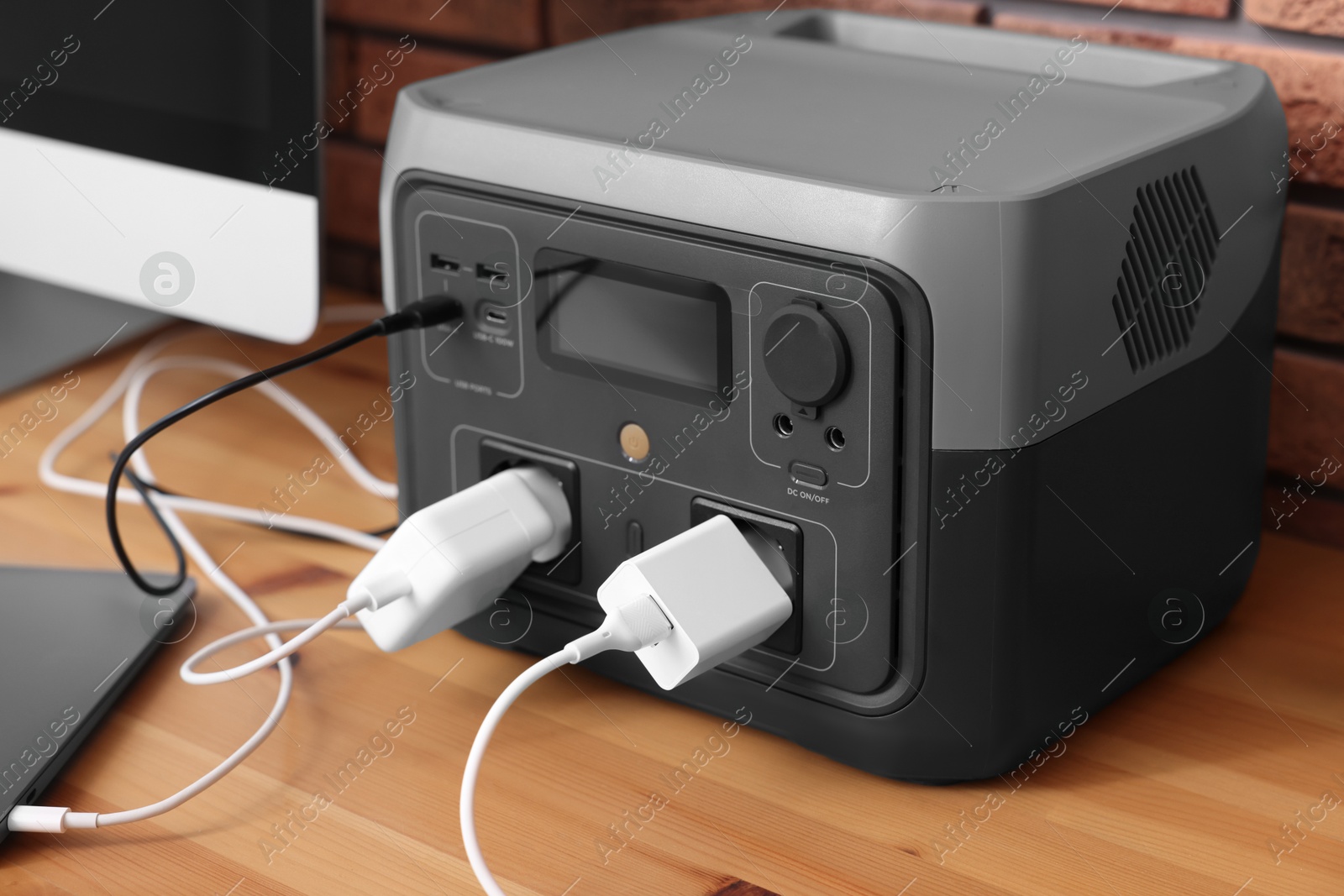 Photo of Devices charging from portable power station on wooden desk indoors