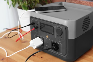 Photo of Smartphone charging from portable power station on wooden desk