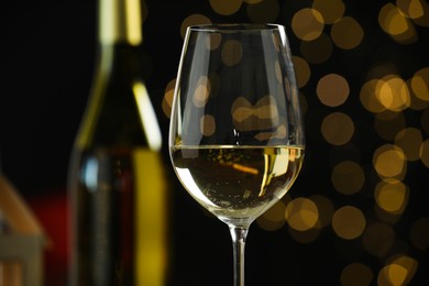 Photo of Glass of white wine against blurred Christmas lights, closeup. Bokeh effect