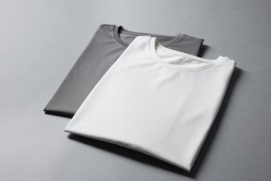 Photo of Different blank t-shirts on grey background. Mockup for design