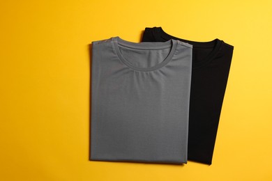 Photo of Different blank t-shirts on yellow background, top view. Mockup for design