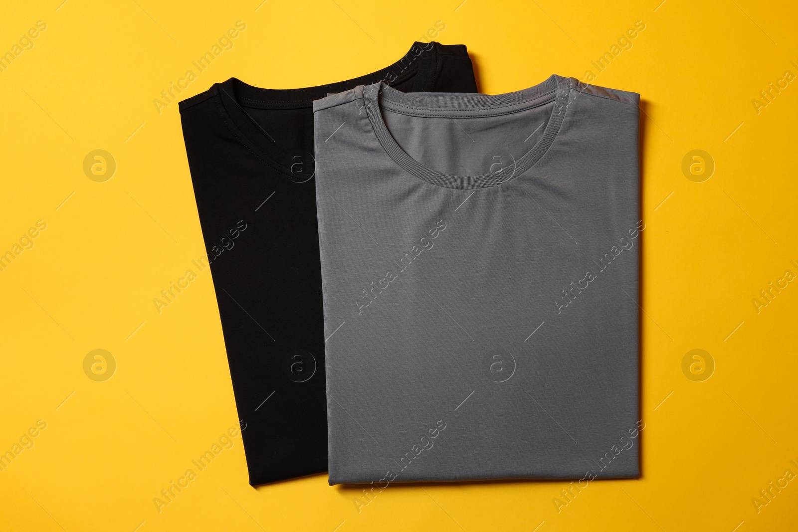 Photo of Different blank t-shirts on yellow background, top view. Mockup for design