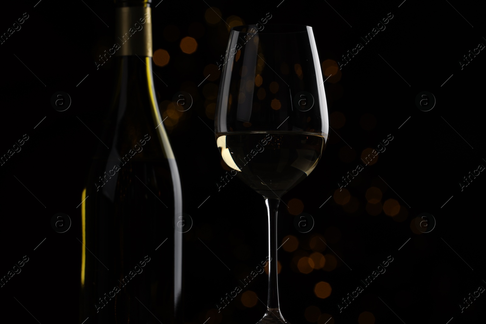 Photo of Wine in glass and bottle on black background, closeup